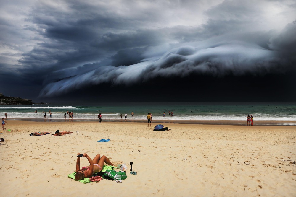 Nature 1st place. A massive 'cloud tsunami' looms over Sydney as a sunbather reads, oblivious to the approaching cloud on Bondi Beach.