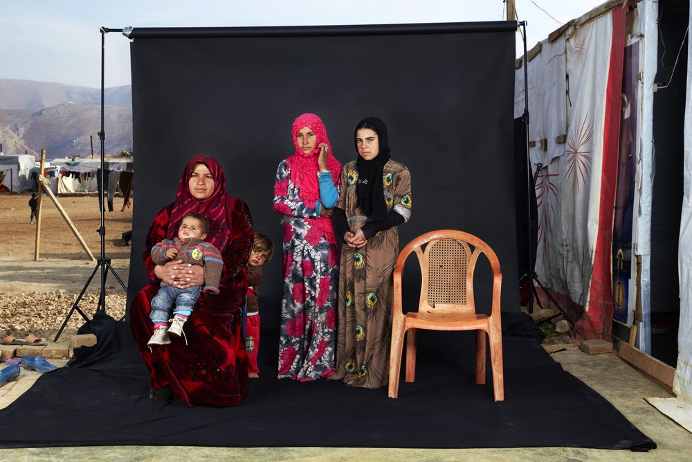 People 3rd place. Portrait of a Syrian refugee family in a camp in Bekaa Valley, Lebanon. The empty chair in the photograph represents a family member who has either died in the war or whose whereabouts are unknown.