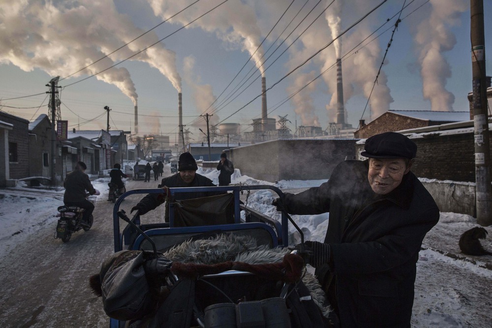Daily Life 1st place. Chinese men pull a tricycle in a neighborhood next to a coal-fired power plant in Shanxi, China.

A history of heavy dependence on burning coal for energy has made China the source of nearly a third of the world's total carbon dioxide (CO2) emissions, the toxic pollutants widely cited by scientists and environmentalists as the primary cause of global warming.