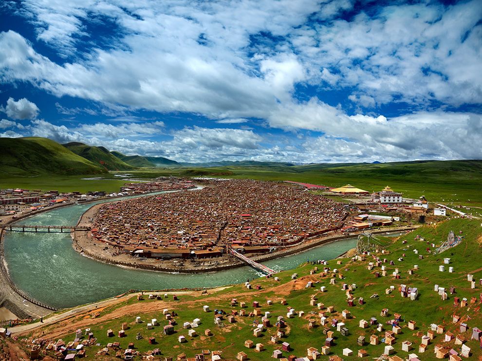 12 River of Ten Thousand Souls. Photograph by Thierry Bornier.      "Dwellings housing Tibetan Buddhist nuns flank Yaqing Temple in China’s Garzê Tibetan Autonomous Prefecture. Your Shot member Thierry Bornier traveled here after learning about it from a friend. Relatively undiscovered, the place’s beauty remains untouched by modernism and tourism, he says. He spent four days near the temple to capture this image with a blue sky and big white clouds in order to give the landscape a 3-D quality."