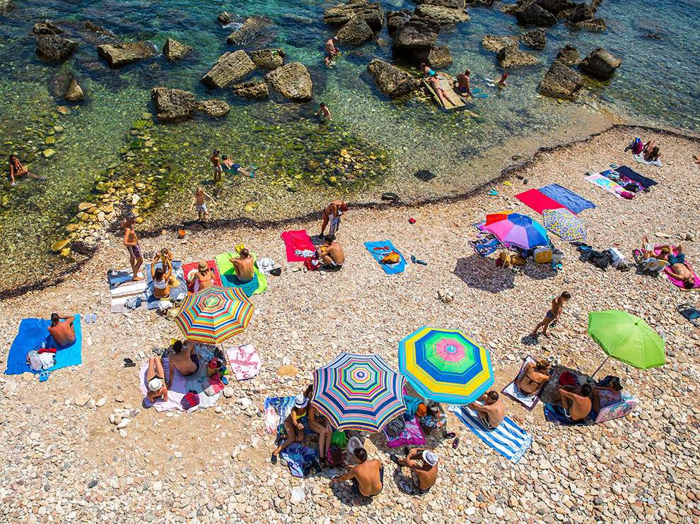 14 Pebbles on the Beach. Photograph by Joe Navin. “I liked the vivid colors from the parasols and the towels, the curve of the waterline, and the bathers across the scene,” says Joe Navin, who took this shot from a road above a beach in Ortigia, Sicily. “The road gives an unusual perspective for a beach shot and it worked well with a wide-angle lens, so it was quite quick to frame and shoot.”