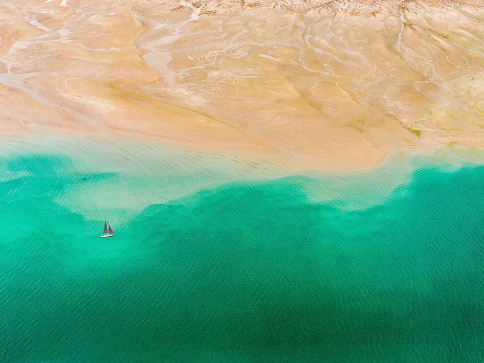 27 Between Land and Sea. Photograph by Abrar Mohsin.      "Though Dubai is known for its grandiose cityscapes, it also has a vast and awe-inspiring natural beauty, writes Abrar Mohsin, who captured this aerial view from a helicopter above the seaside UAE metropolis. “The serene turquoise water and the golden hues in the desert sand present an interesting contrast,” he writes."