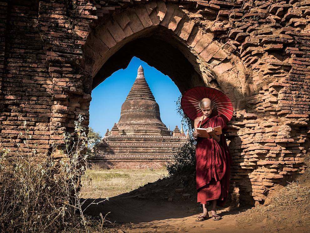4 "A Quiet Spot". Photograph by Nuttawut Jaroenchai. A young monk in Myanmar's ancient city of Bagan has found a quiet spot to read. The archway behind him offers shade and neatly frames a nearby pagoda, thousands of which dot the Bagan landscape.