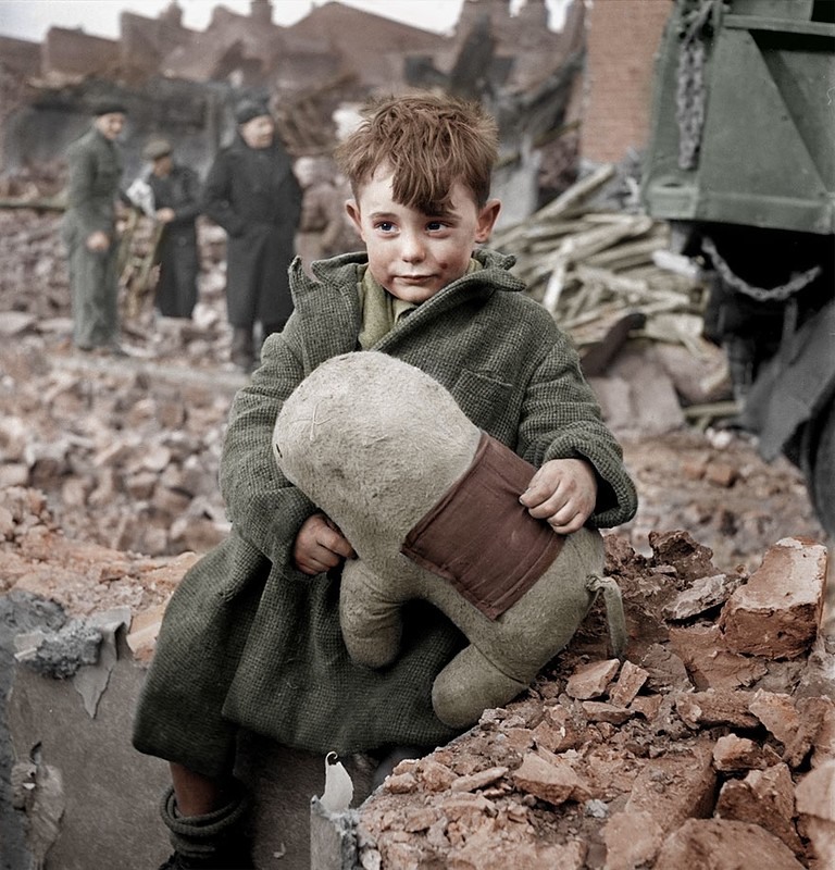 2 Orphaned boy sits on the ruins of the house and holding a stuffed animal, London 1945. Photograph by HansLucifer.